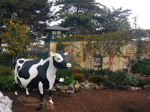 Fake cow in front of painted wall